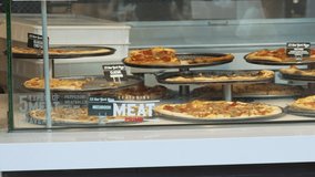 This panning video show a shopping mall food court pizzeria display.
