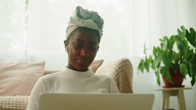 Native African American woman using video call on laptop close-up, virtual conference. Young female student working remotely at computer in living room, happy freelancer. Communicating online.