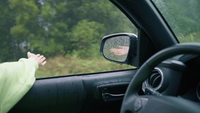 Cinematic inspirational video of young woman traveling by car or camper van with opened window to breathe fresh air of green rainforest, moves hand in rain.Summertime vacation vibes shot on RED camera