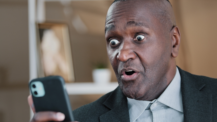 African American old 50s surprised amazed shocked man looking at mobile phone screen reading unbelievable news waving head no disagreement negation refusal shock fear amazing online sms shock reaction Royalty-Free Stock Footage #1092472059