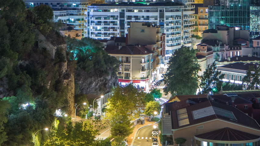 Panorama of Monte Carlo near castle timelapse at night from the observation deck in the village of Monaco near Port Hercules. Roofs of houses and buildings with illumination and hills on background