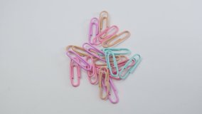 Multicolored close up paper clips on a white background. Back to school. Selective focus. Slow motion