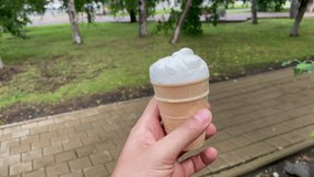 Vanilla and dairy ice cream in hand, selective focus. Walking around the city, pov video