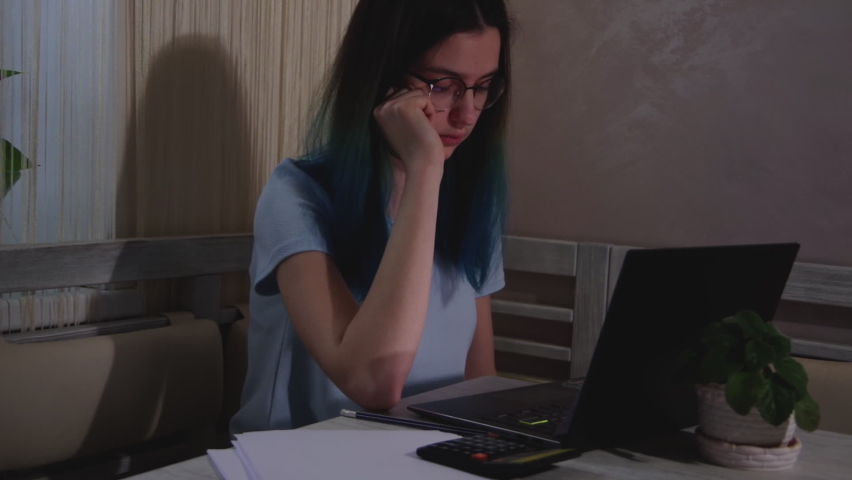 An Asian student or businesswoman works late. A focused and sleepy teenage girl is typing on a laptop and falling asleep at the table .The concept of people who work hard and the burnout syndrome | Shutterstock HD Video #1092473219