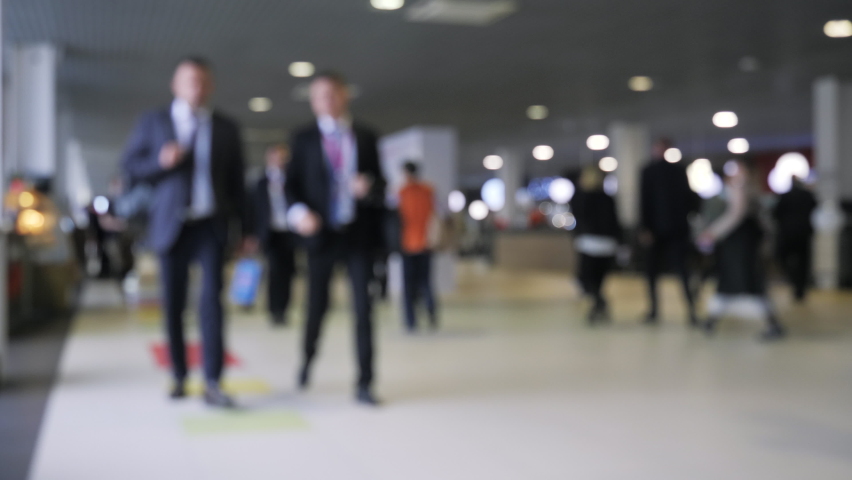 Blurred crowd of people passing by in a shopping or business center. Media. Many defocused people inside shopping mall building.