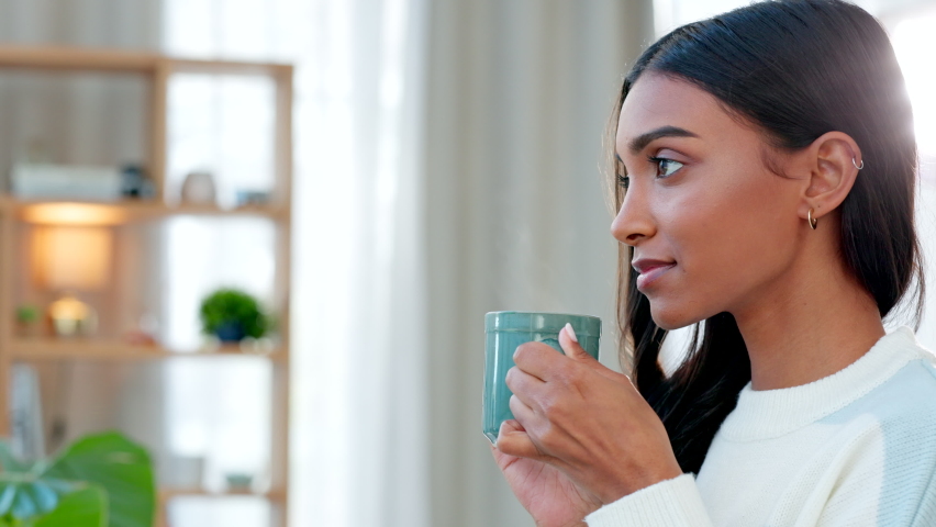 Enjoying a comfortable and cozy tea break. Young woman drinking a hot cup of coffee at home. One beautiful female smelling the aroma of a fresh warm beverage while relaxing at home. Royalty-Free Stock Footage #1092475385