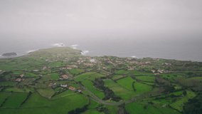 Aerial view of picturesque landscape of Flores Island at sunny day, Azores, Panoramic view of houses surrounding green farm fields at atlantic ocean.