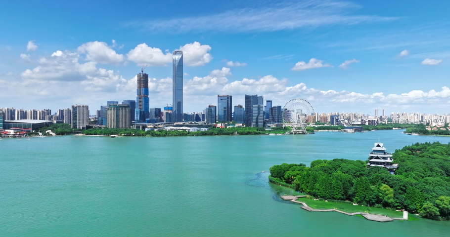 Aerial footage of city skyline and modern commercial buildings with lake natural scenery in Suzhou, China.