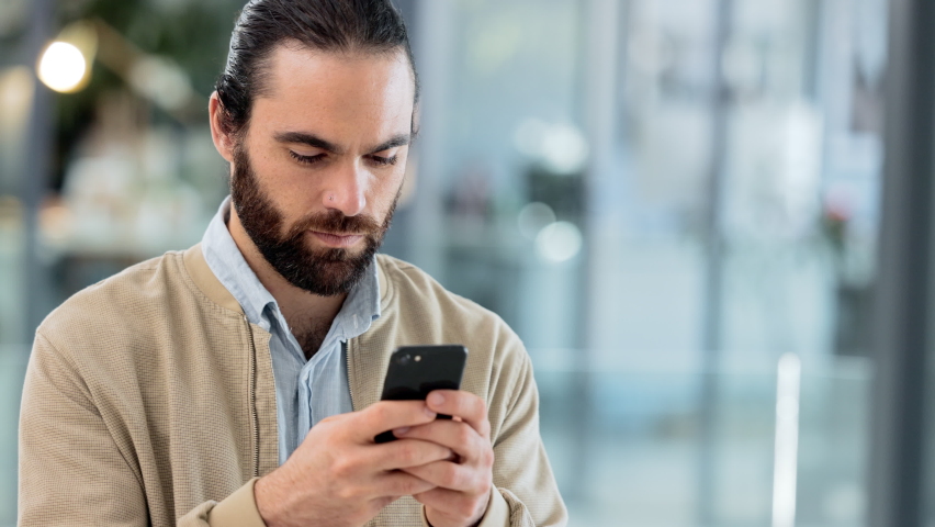 Happy entrepreneur using a phone and receiving an instant loan approval. Successful business man checking text message or email with a happy expression on his face after reading good news online Royalty-Free Stock Footage #1092487189