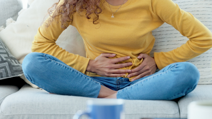 Closeup of a woman with period cramps rubbing her stomach. Young girl suffering from endometriosis and experiencing discomfort, painful belly. A stomachache due to PMS or menstruation cycle | Shutterstock HD Video #1092487359
