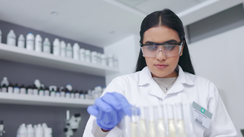 Micro biologist examines liquid bacteria in glassware mixture to invent a vaccine cure for a virus at an innovative research hospital. Young female scientist analysing test tube in a laboratory | Shutterstock HD Video #1092487379