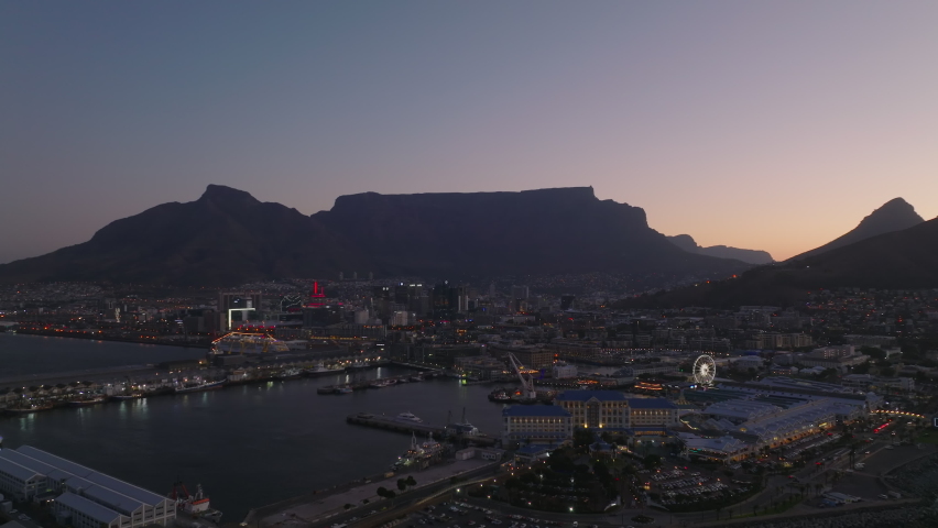 Harbour and entertaining urban borough at waterfront in evening. Forwards fly above sea coast at dusk. Cape Town, South Africa