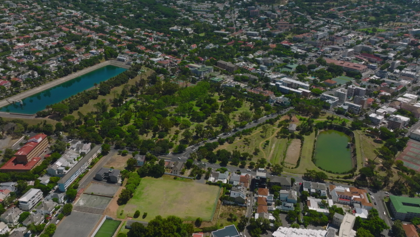 High angle view of De Waal Park with water reservoirs in residential suburb. Tilt up reveal mountains. Cape Town, South Africa