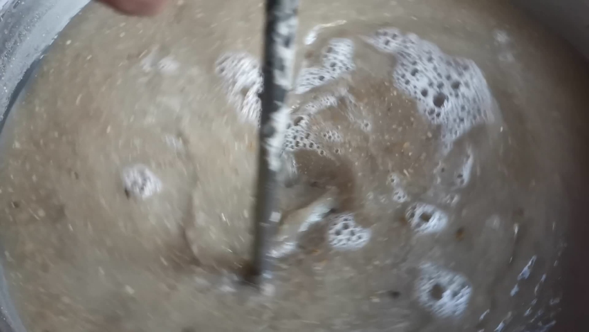 Stirring the malt and water mixture during the mashing procedure of a home brewed pilsner. Slow motion detail shot | Shutterstock HD Video #1092500191