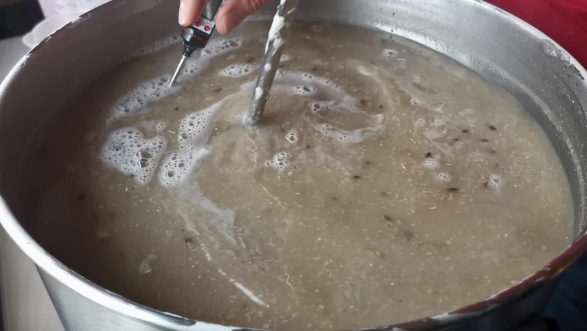 Slow motion footage of the warm brown mash being stirred and its temperature measured. Handheld close up shot of self brewed beer | Shutterstock HD Video #1092500579