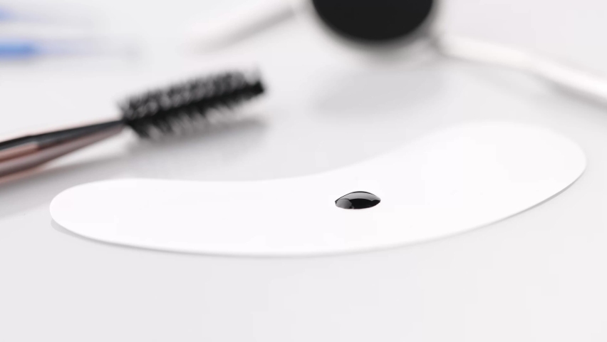 Accessories for eyelash extensions. Beauty master holding curve tweezers with false eyelash, dip it into drop of eyelash glue. Tools for eyelashes extension procedure. Royalty-Free Stock Footage #1092501447