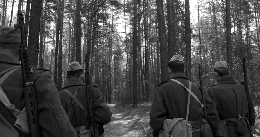 4K Squad Men Dressed As World War II Russian Soviet Red Army Soldiers Marching Through Spring Forest In Sunny day. Soldier Of WWII WW2 Times. Black And White Colors.