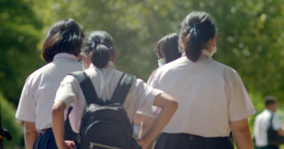 Slow motion back view of the Asian high school students in white uniform wearing the masks to protect COVID-19 are going back to school when school starts. Royalty-Free Stock Footage #1092508469