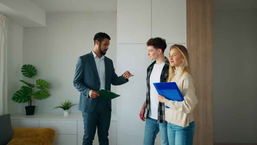 Happy young couple buying their new home and meeting real estate agent in apartment. Royalty-Free Stock Footage #1092509485