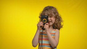 Litttle curly girl cinematographer is using retro camera for shooting in studio