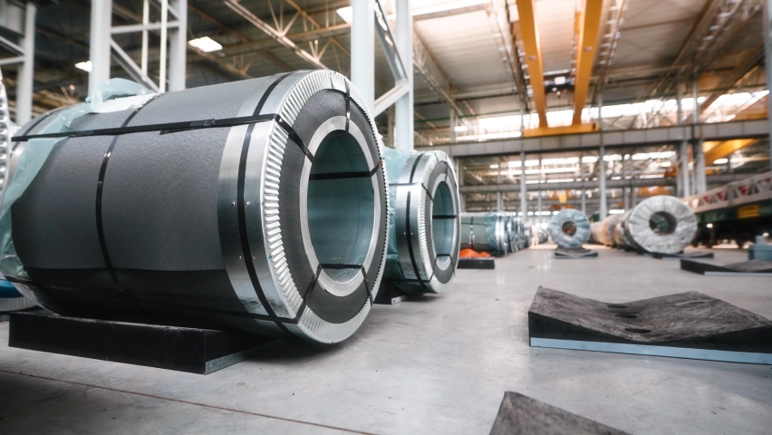 Industrial workshop and warehouse for storage and distribution of products of a metallurgical plant. Coiled steel is stored in rows in a modern warehouse. Royalty-Free Stock Footage #1092512289