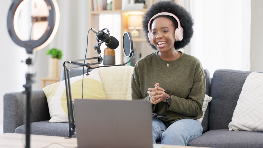 Cool afro influencer, journalist or podcast host using a digital tablet, talking into microphone, broadcasting news and wearing headphones. Excited woman using technology to promote on air from home | Shutterstock HD Video #1092513311