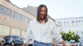 Funky and carefree young woman dancing and looking excited in the city. Happy and positive latino female feeling carefree, moving her body to the beat of music while traveling and commuting in town