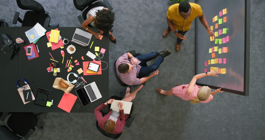 Overhead view of creative team in a meeting brainstorming ideas. Professional colleagues working together to plan a solid marketing strategy. Group in close collaboration inside boardroom Royalty-Free Stock Footage #1092515259
