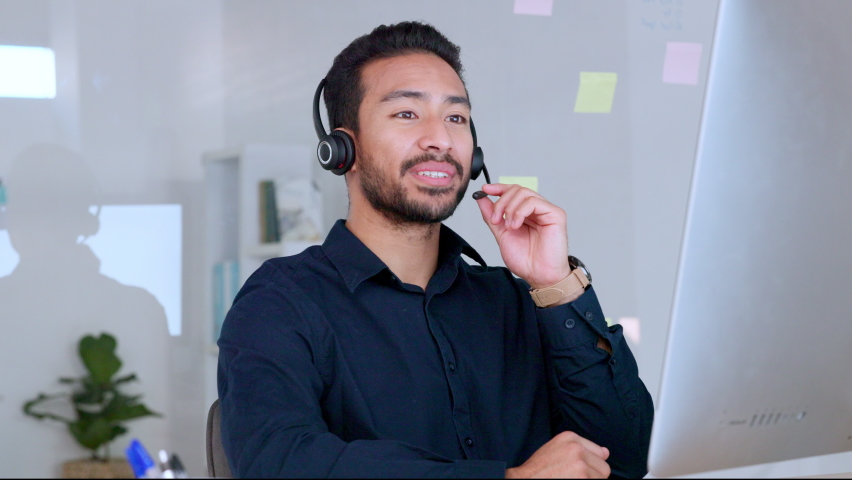 Male call center agent talking on headset and explaining product while working in an office. Confident and cheerful salesman looking at computer and giving advice for customer service and support Royalty-Free Stock Footage #1092518079