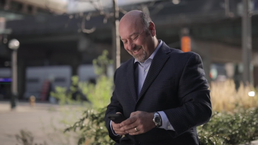 Man reading and texting and laughing with blurred background and cars driving by