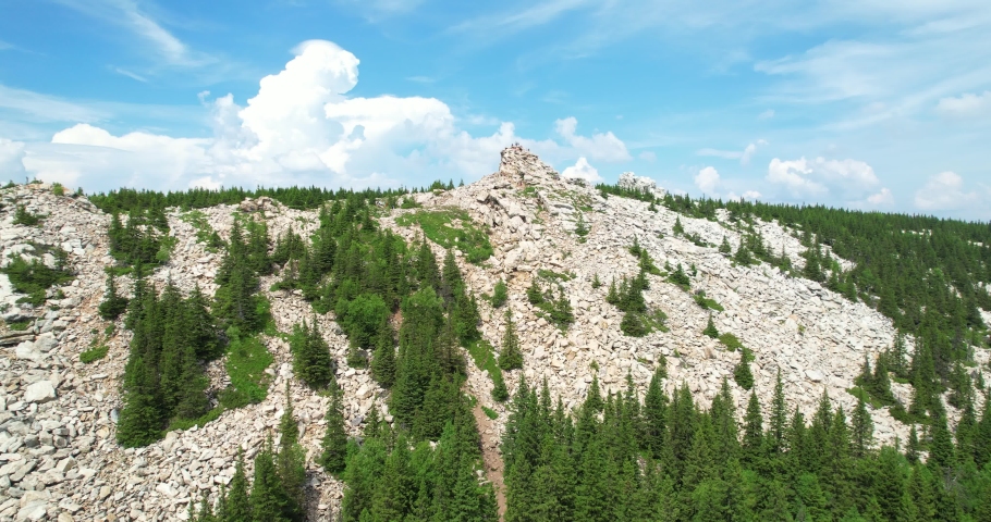 Rocks on top of a mountain range. Mountain landscape with beautiful sky in summer. Stony placers of white quartzite. Forest and mountains. Rocks at the top of the ridge