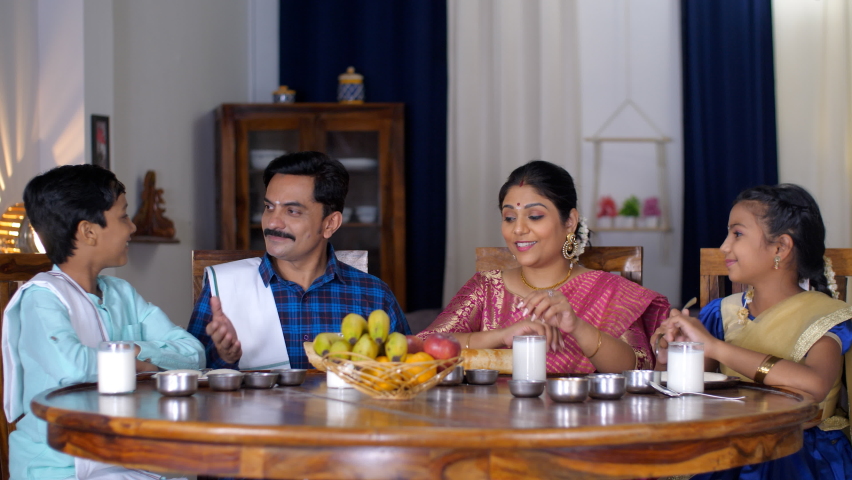 A happy South Indian couple and their adorable kids having lunch  dinner together - quality time, family bonding. A cheerful South Indian family together at the dining table - Nuclear family, Indi... Royalty-Free Stock Footage #1092526375