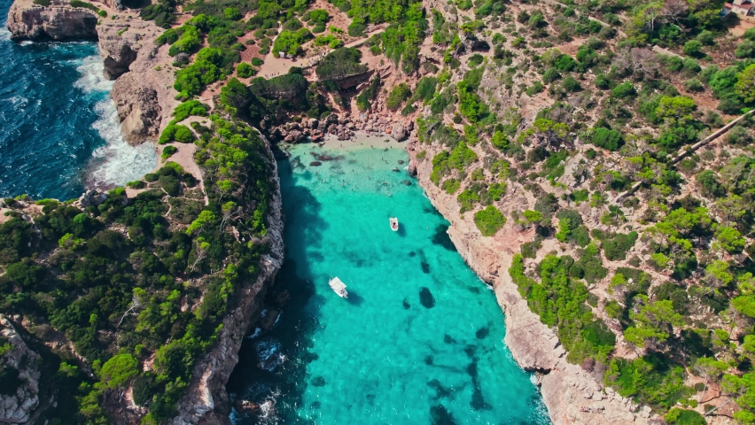 Beautiful cave rocky beach with blue water on a sunny day in Majorca, Spain. Panoramic view from above of a famous tourist attraction Caló del Moro Beach by the coast in Mallorca, Balearic Islands. Royalty-Free Stock Footage #1092538983