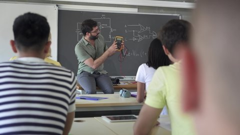 High School Teacher explaining electrical voltage tester device To Pupils learning In Technology Electronics course - Βίντεο στοκ