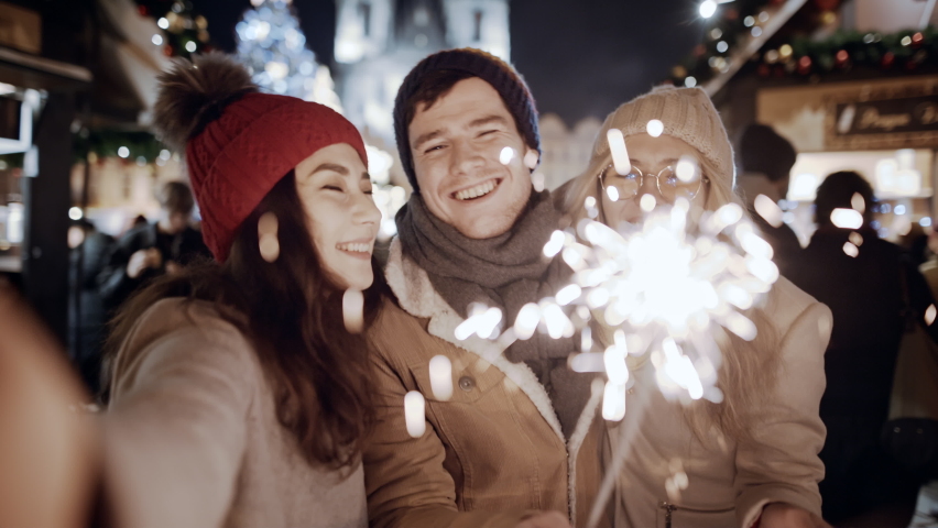 Beauty young multiracial friends asian girl use smartphone communicating, podcast video chat Europe night street. Woman looking at phone selfy with falling sparkling glowing sparklers fireworks light. Royalty-Free Stock Footage #1092541977