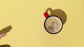 Woman hand holding a cup of coffee on yellow background. Minimalist style. Stop motion animation. - Powered by Shutterstock - Get 15% off with code: PIKWIZARD15