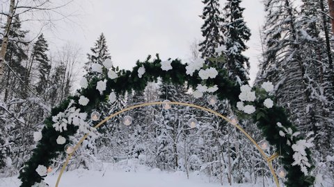 Beautiful winter wedding arch decorated with spruce branches and small light bulbs. Smooth camera movement