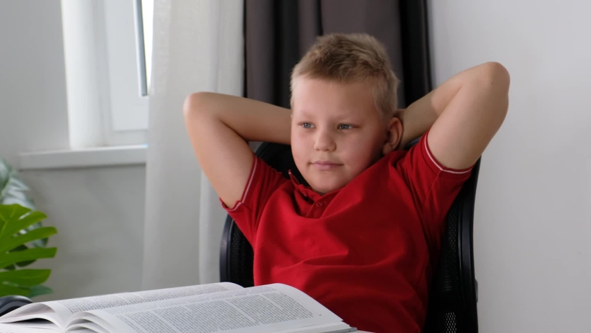 Relaxed happy school boy resting and smiling, healthy lazy calm rest, dreaming on a chair with book | Shutterstock HD Video #1092549995