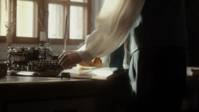 A man writer dips his pen into an inkwell and prepares to write a book in his workshop. Cosplay of the Middle Ages. Cinematic concept. Close-up feather. 4K video, RED camera