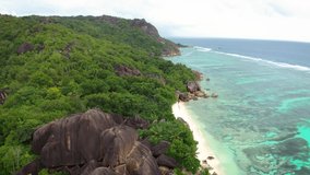 Aerial pan right of Anse Source D'argent beach at the La Digue Island, Seychelles, with turquoise water of the Indian Ocean, palm trees and amazing granite rock formations. 4K UHD video.
