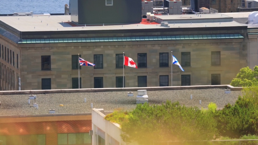 Canada Flag, British Flag and the province Nova Scotia flags flying high on Canada Day on top public building, Halifax, Nova Scotia, Canada