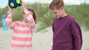Slow motion 4K video of walking teenage children on wooden pathway at white beach in north germany at summer vacation