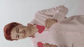 Message video of dancing woman with paper hearts over her eyes on a white background. Valentine's Day, mother's day concept. . Love in your eyes, romantic concept.Video for the vertical story.
