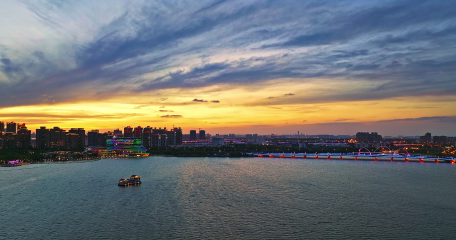 Aerial footage of city skyline and modern buildings with lake scenery in Suzhou at sunset, China.