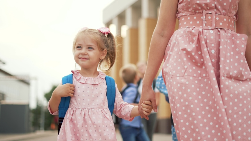 Happy family back to school. Mom and daughter go to school by hand. Girl with backpack holds her mother by hand. Happy family concept. Back to school. Mom and daughter go to school with a backpack Royalty-Free Stock Footage #1092564703