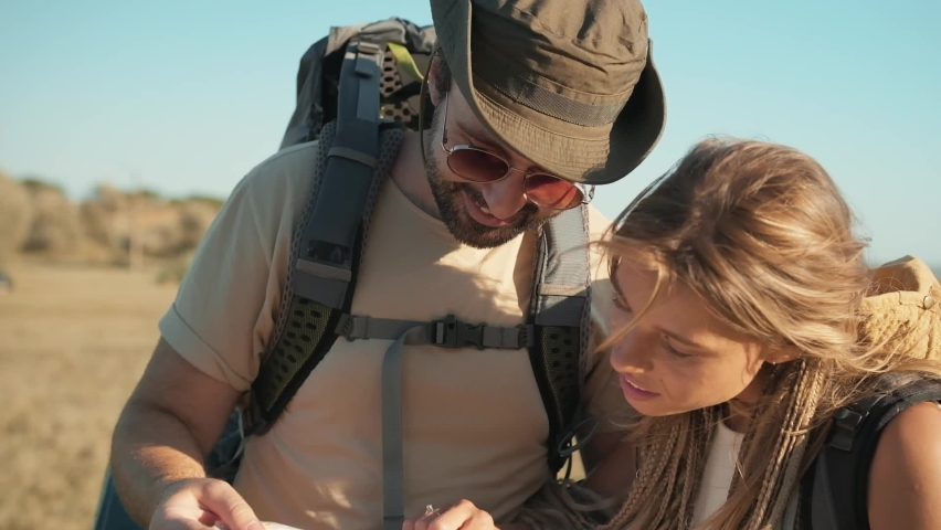 Close-up view of smiling tourists couple looking at the map near the river