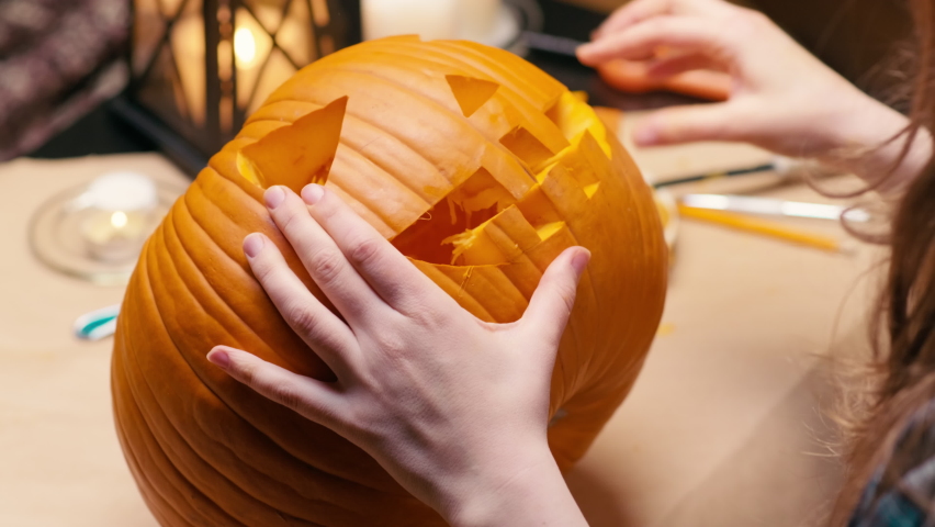 Preparing pumpkin for Halloween. Woman sitting and cleaning carved halloween Jack O Lantern pumpkin at home for her family. Royalty-Free Stock Footage #1092566493