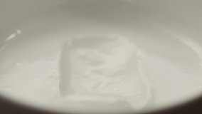 Slow motion macro shot of scooping white yogurt with a spoon