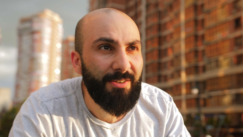 Portrait of a bearded man in the yard of a house training on a stationary outdoor simulator.