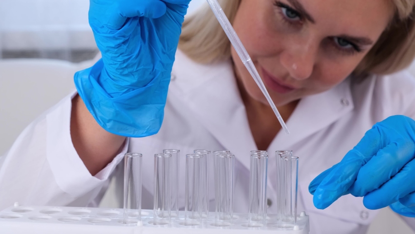 Professional scientist laboratory assistant takes and examines samples using a micropipette and test tubes to work under a microscope in a laboratory, close up. | Shutterstock HD Video #1092580829
